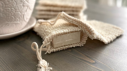 artisan bar soap in a beige sisal soap bag on dark wooden table