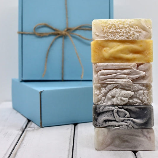 A stack of six artisan soap bars displayed in front of 2 blue gift boxes