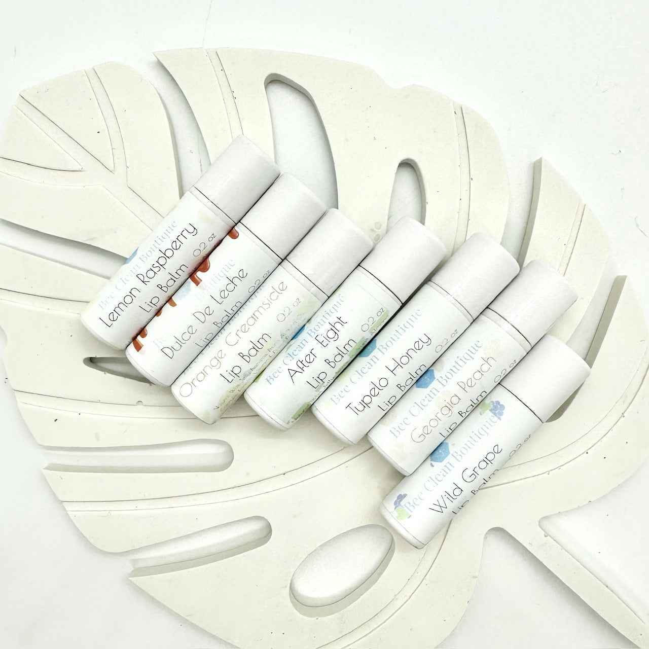 7 tubes of lip balms in a variety of flavours diplayed on a palm leaf tray