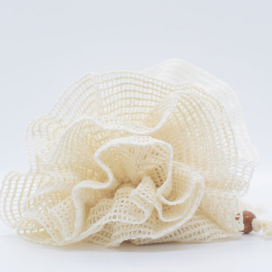 a beige shower loofah on display on white surface