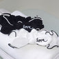 one black and one white fabric headbands with the word Love embroidered on a pile of folded white towels