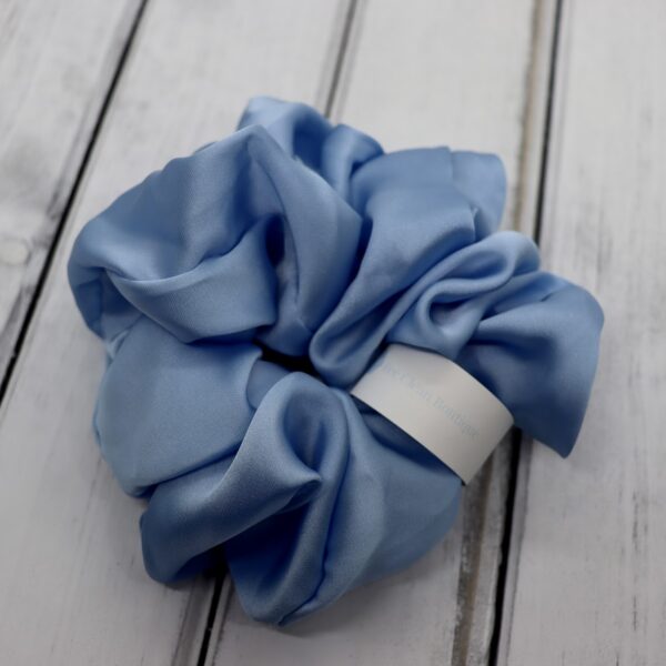 Large blue satin hair scrunchie on a wooden surface