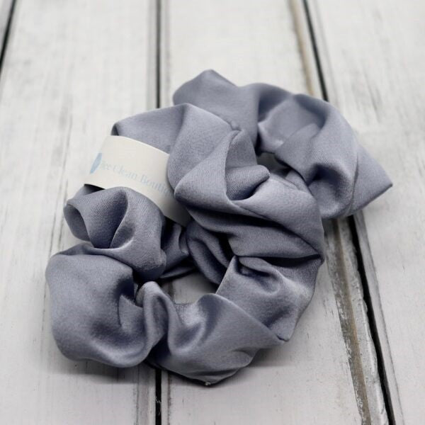 2 grey satin hair scrunchies on a wooden surface