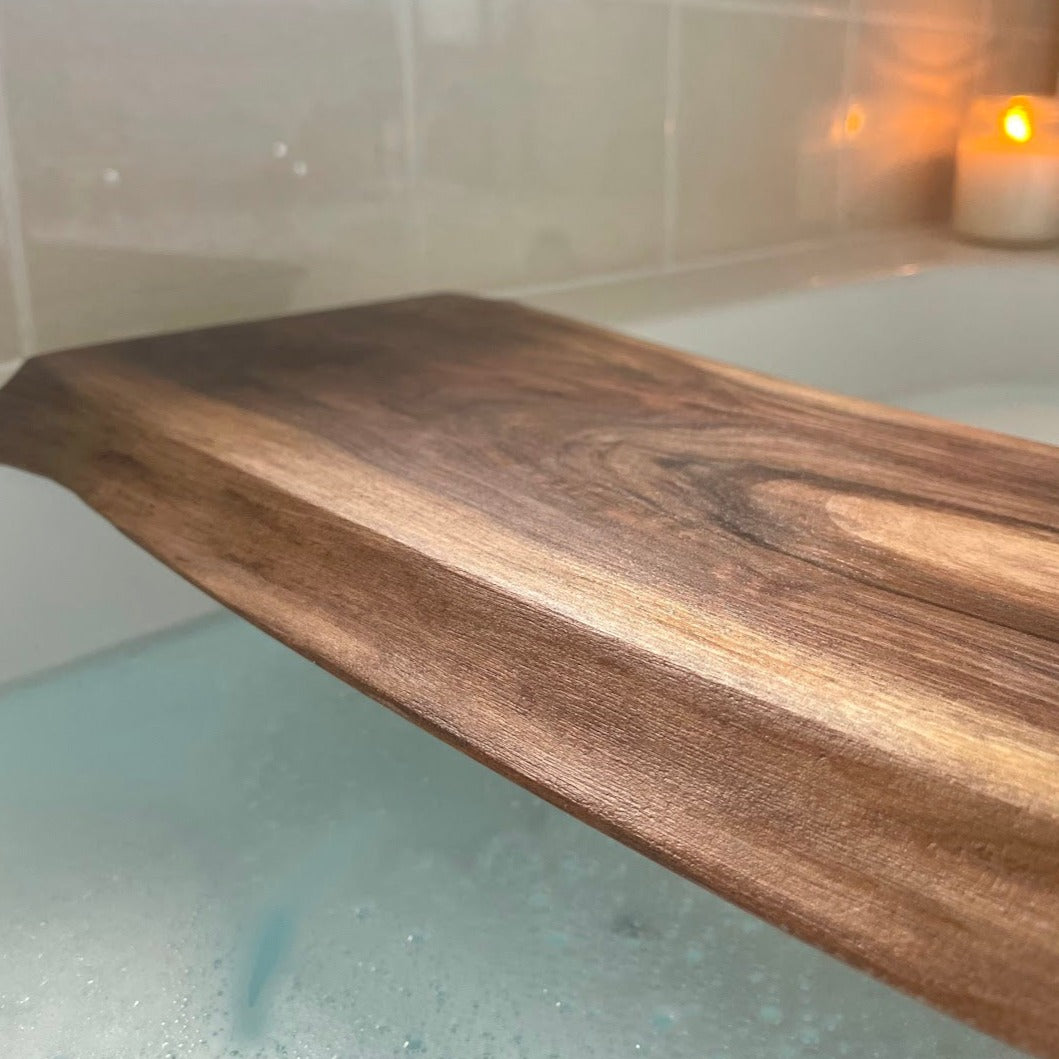 a walnut bath caddy is shown closeup over a bathtub filled with water