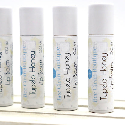 Four small tubes of Tupelo Honey flavoured lip balm standing on a wooden platform